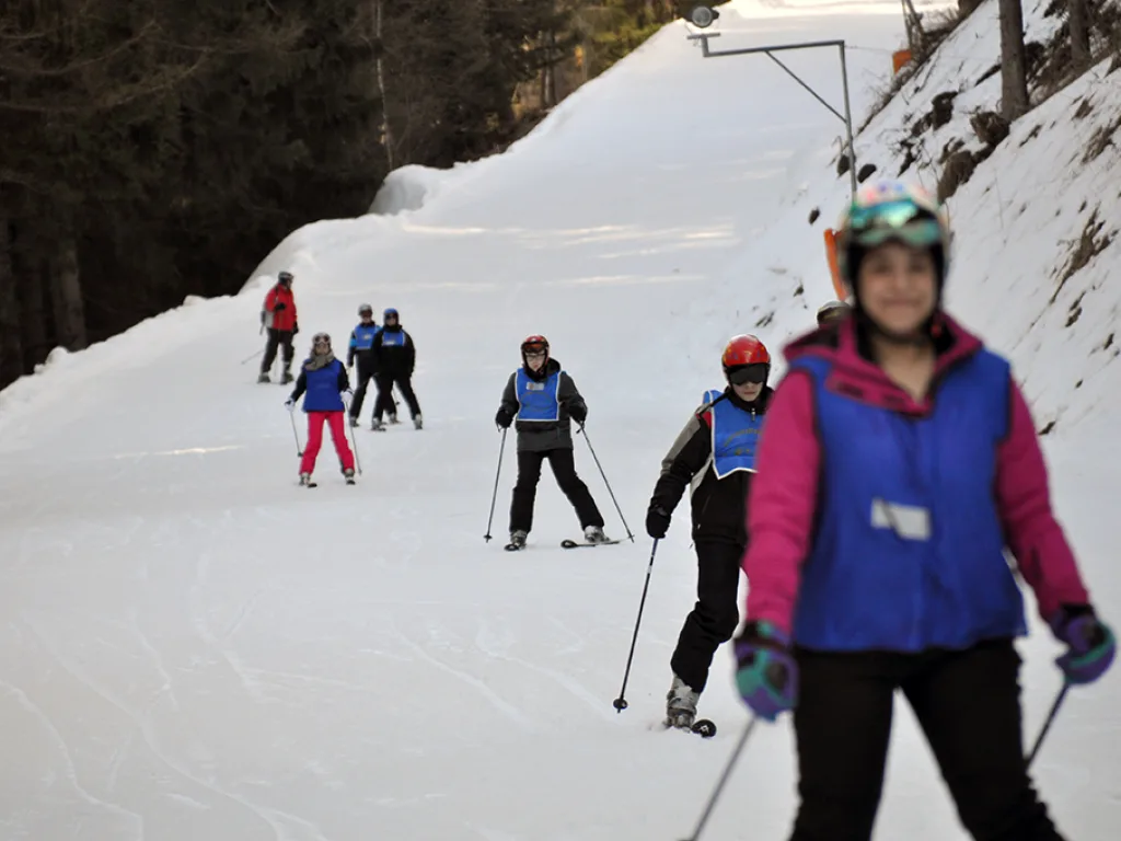 Skifahrerin in pinker Jacke am Pistenrand.